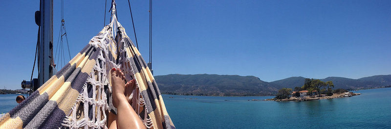Le point de vue d'une personne allongée dans un hamac sur un bateau. Elle a les jambes croisées et voir le paysage (mer et terre) tout autour d'elle.