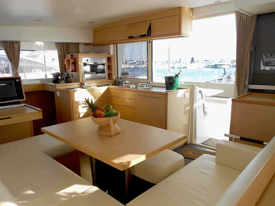 Pendant une croisière en catamaran en Crète, vous découvrirez le carré, pièce centrale du bateau où se trouve des banquettes pour s'asseoir et la cuisine avec une vue panoramique sur le paysage.